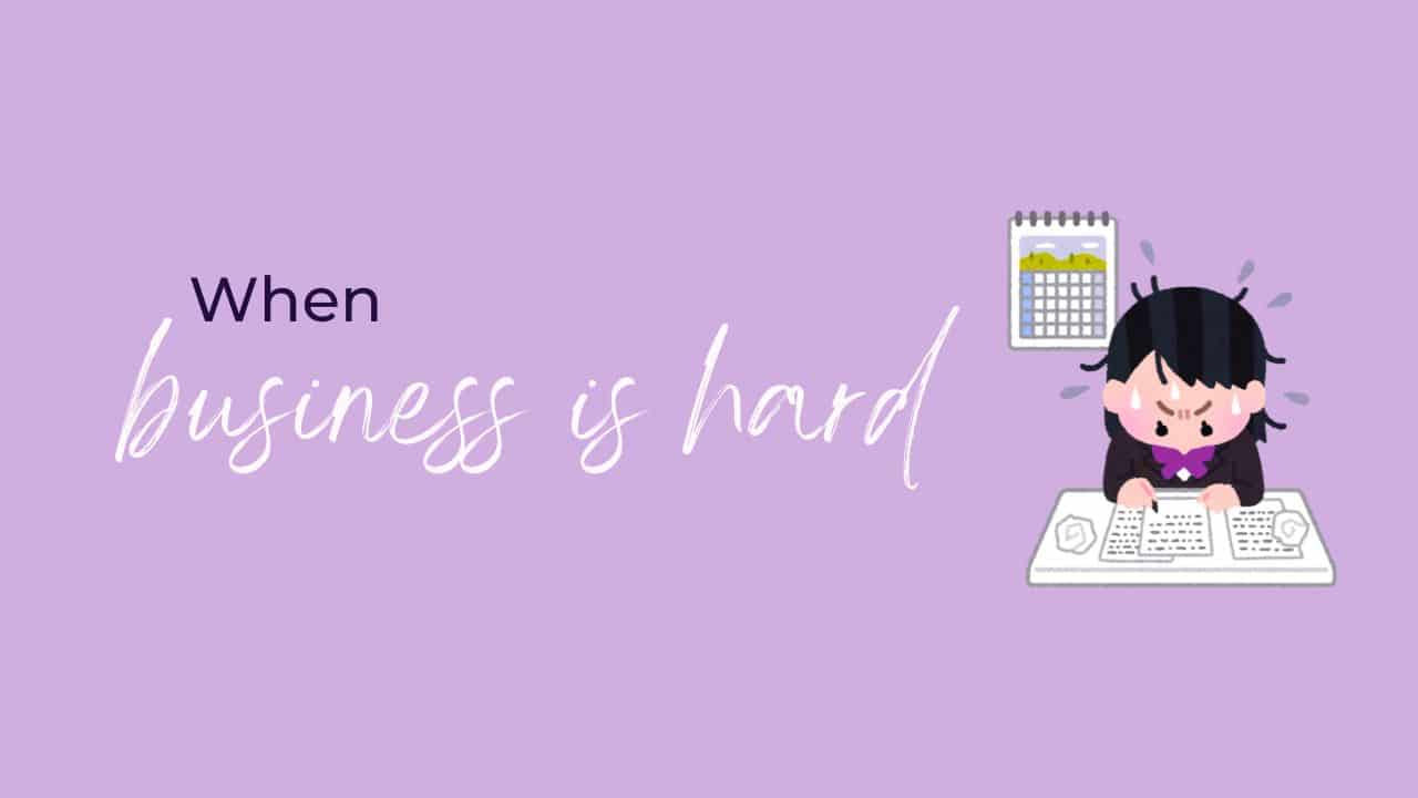 Lavender background with the words ‘When business is hard’ beside an illustration of a frustrated woman sweating over her desk with papers and a calendar behind her — symbolising the challenges of running a small business.